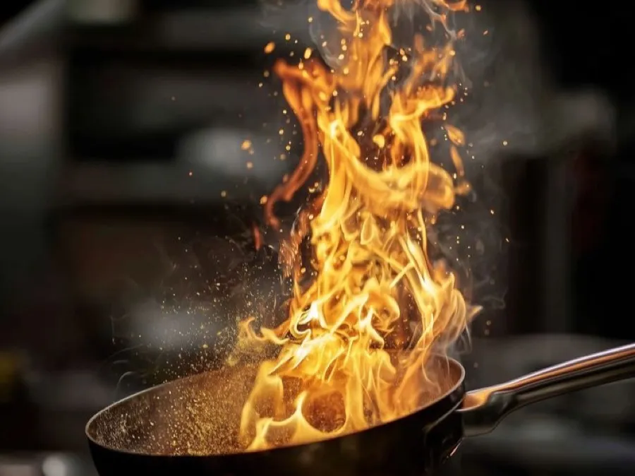 A flambé pan alight in a professional kitchen